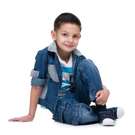 A cute little boy sits on the white backgroundの写真素材