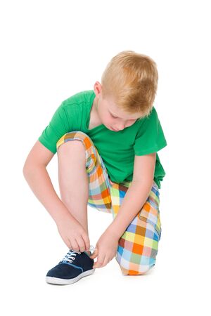 A boy tying shoelaces on the white backgroundの写真素材