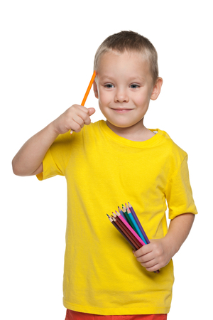 A little boy with pencils is standing on the white backgroundの写真素材