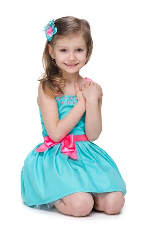 A happy little girl sits on the white backgroundの写真素材
