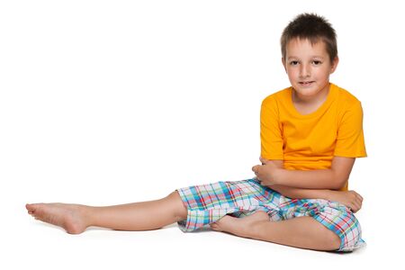A cute smiling little boy sits on the white backgroundの写真素材