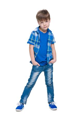 A serious little boy stands against the whiteの写真素材