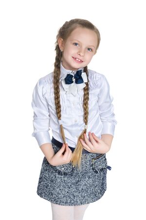 A young girl with pigtails stands against the white backgroundの写真素材
