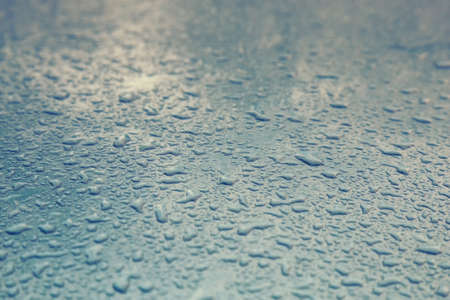 Water drops on metal background with reflection blurred on the edges. Image processing with color filter effectの写真素材