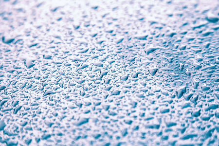 Water drops on metal background with reflection blurred on the edges. Image processing with blue color filter effectの写真素材