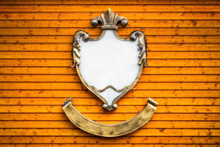 Emblem with frame from metal and white background on wooden wallの写真素材