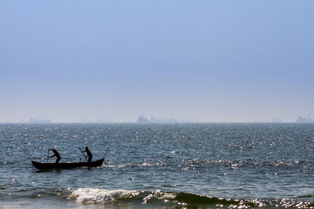 Boat with fishermans at Arabian sea. Cargo ship on the backgroundの写真素材