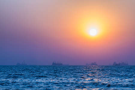Scenic view of beautiful sunset above the Arabian sea. Cargo ship on the backgroundの写真素材
