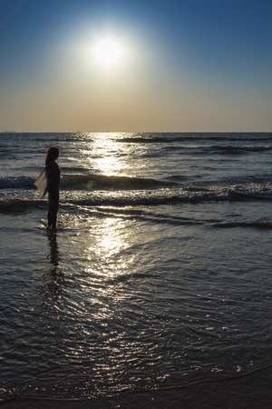 Scenic view from beach in Goa to beautiful sunrise above the Arabian sea. Silhouette of woman or girl looks at seaの写真素材