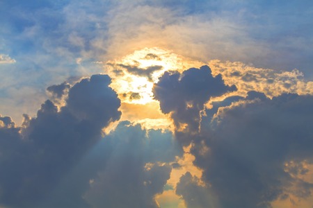 Sun under clouds on blue sky backgroundの写真素材