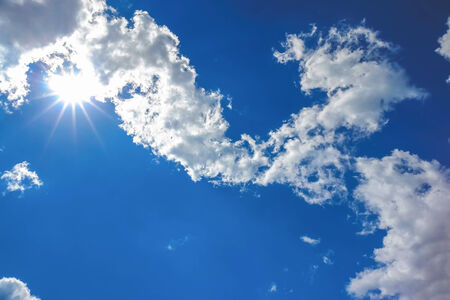 Sun and white clouds on blue sky backgroundの写真素材