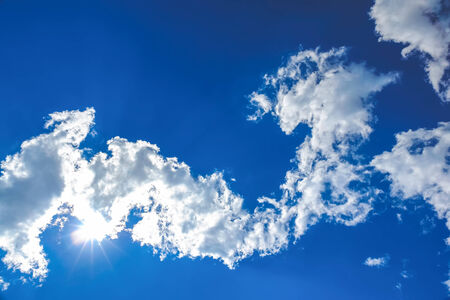 Sun and white clouds on blue sky backgroundの写真素材
