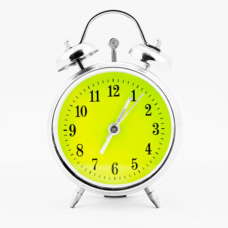 Alarm clock on white background. Showing time five minutes past sevenの写真素材