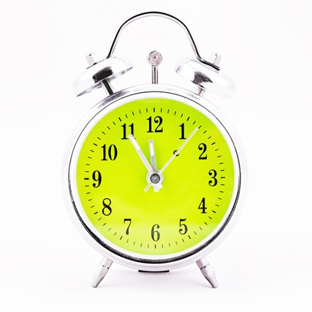 Alarm clock on white background. Showing time five minutes before twelveの写真素材