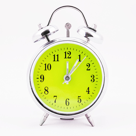 Alarm clock on white background. Showing time five minutes past twelveの写真素材