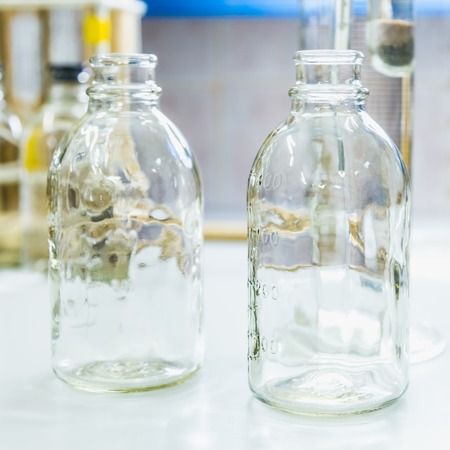 Empty glass bottles on table. Research laboratory glasswareの写真素材