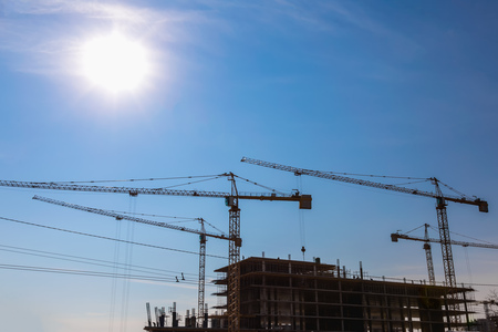 Construction cranes on building site on sky backgroundの写真素材