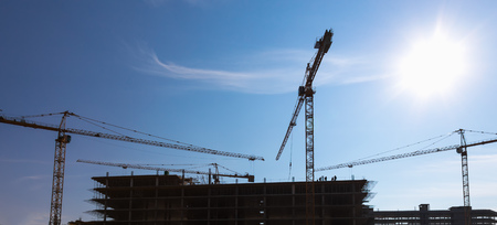 Construction cranes on building site on sky backgroundの写真素材