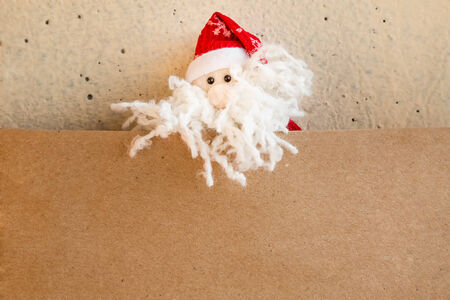 Christmas Santa Claus or Father Frost with greeting brown blank card from craft paper on plaster backgroundの写真素材