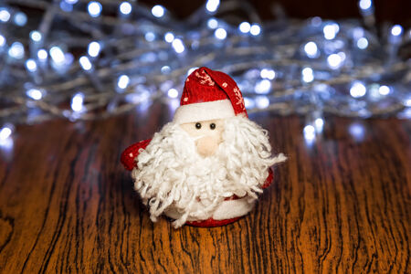 Santa Claus or Father Frost with Christmas lights at background on wooden surfaceの写真素材
