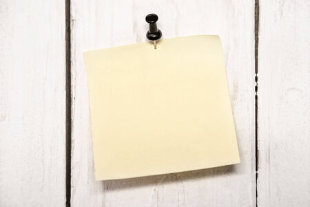 Yellow blank note paper with push black pin on wood backgroundの写真素材