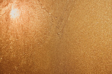 Ice and frost background over the sun on frozen window. Colored in yellow or gold tone. Selective focus at center with blur edges of imageの写真素材