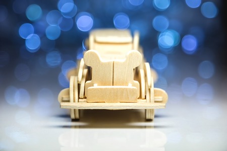 Old toy vintage wooden automobile on christmas lights background. Selective focus on face standing wood carの写真素材