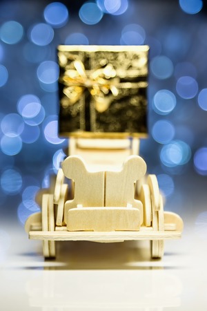 Old toy vintage wooden automobile and gift box on christmas lights background. Selective focus on face standing wood car and blurred gift boxの写真素材