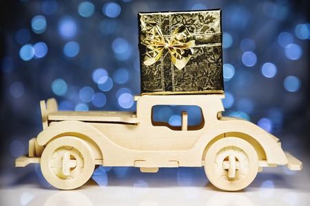 Old toy vintage wooden automobile and gift box on christmas lights backgroundの写真素材