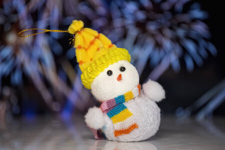 Snowman toy on blurred firework at black backgroundの写真素材