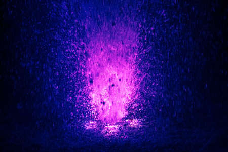 Colorful fountain splashes violet and blue color of water drops on a black backgroundの写真素材