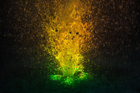 Colorful fountain splashes yellow and green color of water drops on a black background
