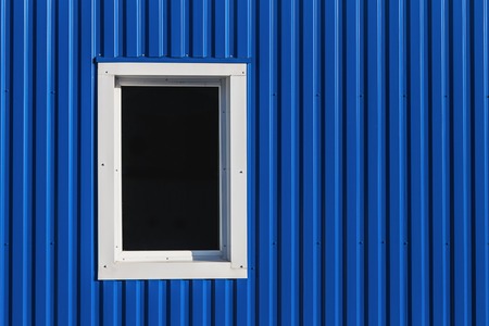 White window in blue color metal siding wallの写真素材
