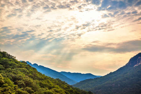 Mountains with green trees landscape and cloudy sky with sunbeams in South Koreaの写真素材