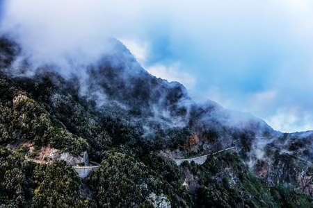 Clouds over mountain peak with winding road in Tenerife Canary island, Spainの写真素材