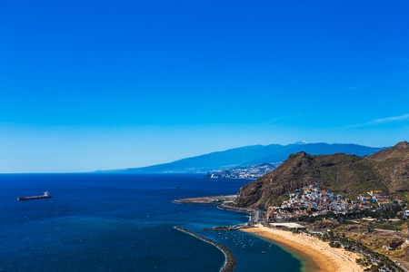 Santa Cruz city and beach or playa Las Teresitas on the coast of Atlantic ocean with ship on Tenerife Canary island, Spain at spring or summer. Teide volcano at backgroundの写真素材