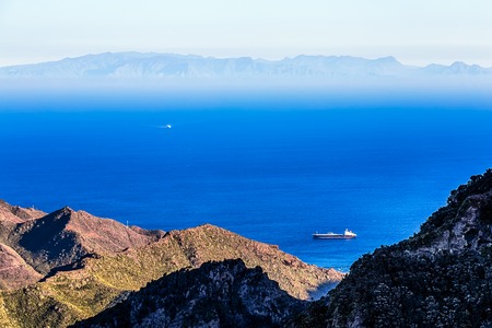 Cargo ship in the bay. Aerial view from rock or mountain. Island on horizonの写真素材