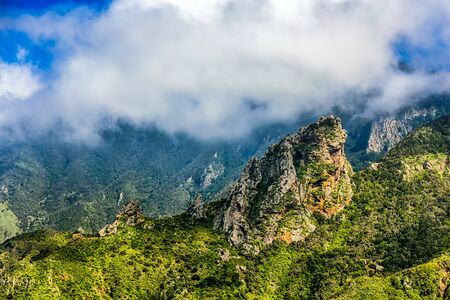 Rocks and green mountain with cloudsの写真素材