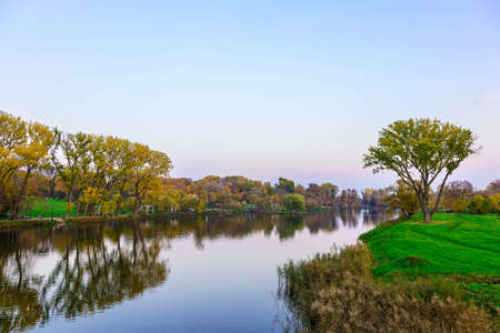 River with Reflecting Trees and Sky in Autumn Park at Sunsetの写真素材