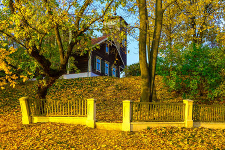 Country Home with Fence on Knoll in Fallen Leaves In Autumnの写真素材