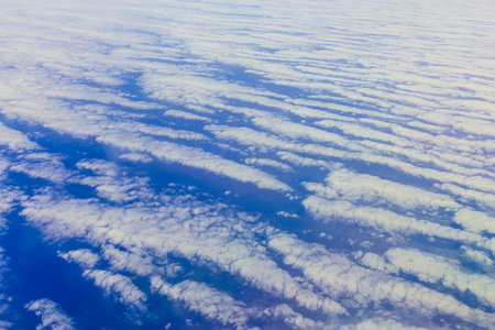 View on blue sky above white clouds and cloudscape from the window of plane