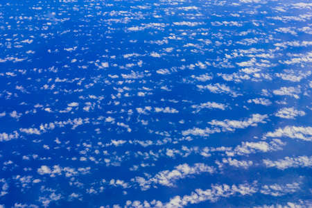 View on blue sky above white clouds or cloudscape from the window of aircraftの写真素材