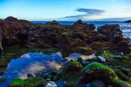 Stone Shore of Atlantic Ocean with Sky Reflection in water on Tenerife Canary Island in Spainの写真素材