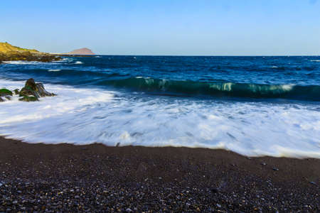 Stone Shore of Atlantic Ocean with Waves on Tenerife Island at Dayの写真素材
