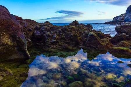 Stone Coast of Ocean with Sky Reflection in water on Tenerife Canary Islandの写真素材