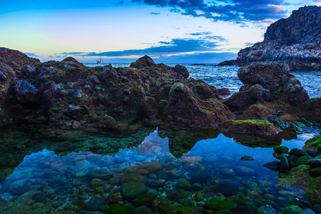 Stone Coast or Shore of Atlantic Ocean with Sky Reflection in water on Tenerife Canary Island in Spainの写真素材
