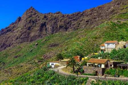 Small Village and Buildings in Green Mountains Landscape on Tenerife Island at Dayの写真素材