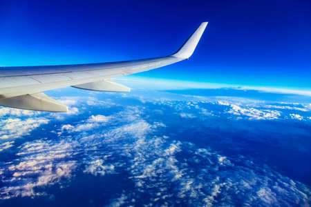 Wing of Plane at Blue Sky Background above Cloudsの写真素材