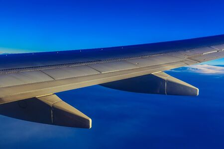 Wing of Plane at Blue Sky Background above Cloudsの写真素材