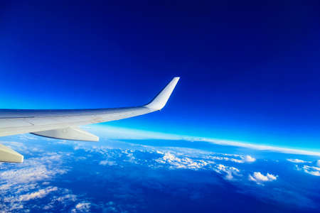 Wing of Plane at Blue Sky Background above Cloudsの写真素材
